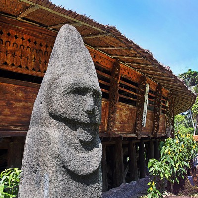 Megalith statue in front of traditional house in Dahana village, Gunungsitoli.